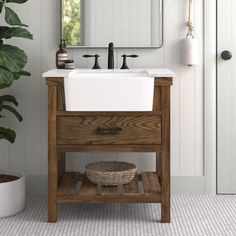 a white sink sitting under a bathroom mirror next to a wooden stand with two faucets