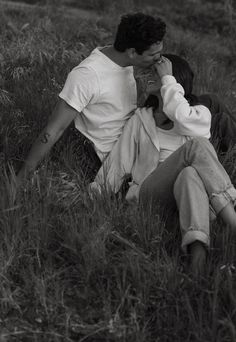 a man sitting in the grass talking on a cell phone while holding his hand to his face