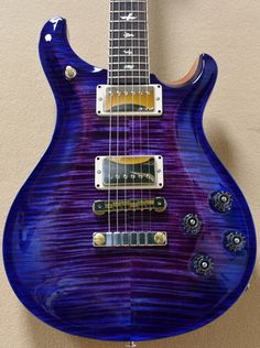 an electric guitar hanging on the wall with it's blue body and purple top