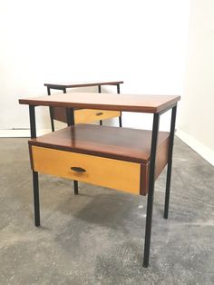 two wooden tables with black metal legs and one has a drawer on the bottom that is open