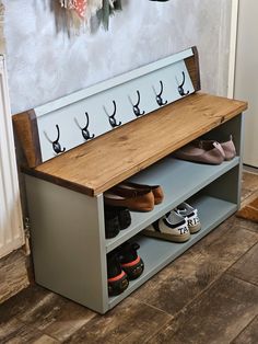 a wooden bench with shoes on it in front of a wall mounted coat hanger