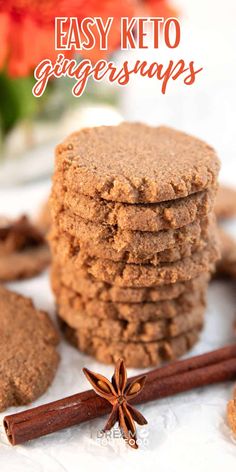 several cookies stacked on top of each other with cinnamon sticks in the foreground and an orange flower in the background