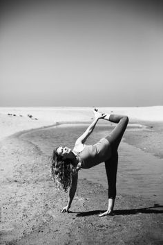 a woman is doing yoga on the beach