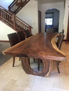 a large wooden table sitting in the middle of a living room next to a stair case