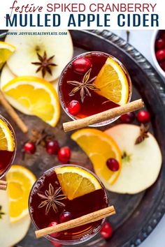 two glasses filled with mulled apple cider on top of a metal platter