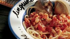 pasta with clams and tomato sauce in a blue and white plate on a table