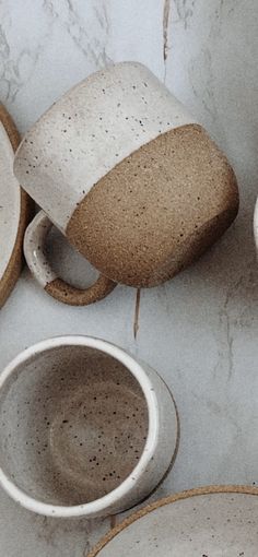 several cups and saucers sitting on a counter top, with one cup in the middle