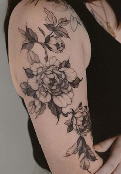 a woman with a black and white flower tattoo on her arm, showing off the shoulder