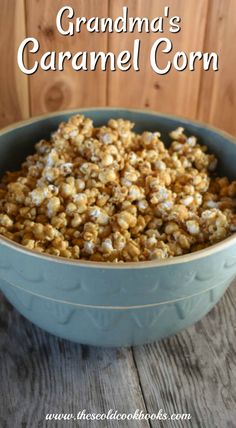 a blue bowl filled with caramel popcorn on top of a wooden table next to a sign