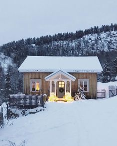 a small wooden house in the middle of a snowy field