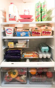 an open refrigerator filled with lots of food next to milk and other foodstuffs