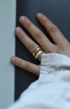 a person's hand with two gold rings on it