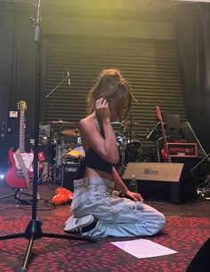 a woman sitting on the floor in front of a microphone