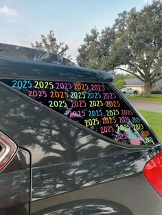 a car that has been decorated with numbers on the back window and is parked in front of a house