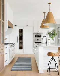 a kitchen with wooden floors and white cabinets, an island countertop and stools