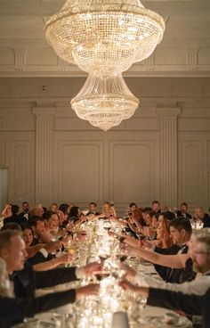 a group of people sitting at a long table with wine glasses in front of them