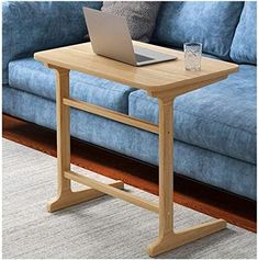 a wooden table with a laptop on it in front of a blue couch and rug