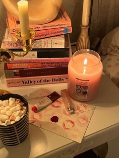 there is a candle and some books on the table next to each other with candles in front of them