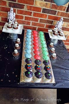 a table topped with cupcakes covered in frosting next to a brick wall