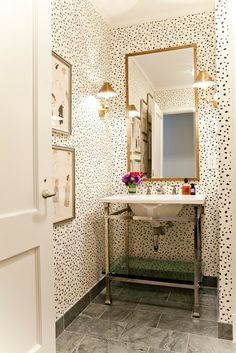 a white sink sitting under a bathroom mirror next to a wall covered in black and white dots