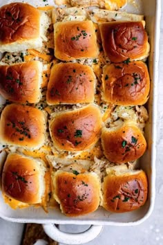 a casserole dish filled with hot dogs, cheese and herbs on bread rolls