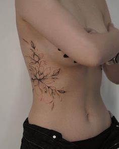 a woman with a flower tattoo on her stomach is looking at the camera while holding her arm behind her back