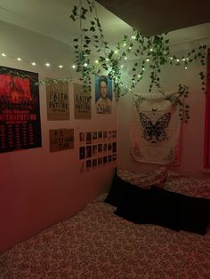 a bedroom with pink walls and posters on the wall above the bed is lit by string lights