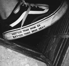 black and white photograph of someone's shoes with words written on the soles