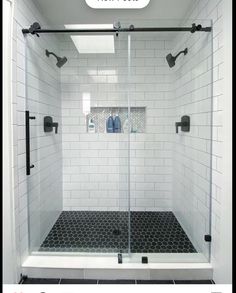 a shower with black and white tile on the floor