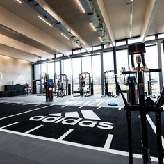 an indoor gym with various equipment and people in the background looking out on the city