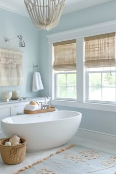 a large white bath tub sitting next to two windows in a bathroom with a rug on the floor