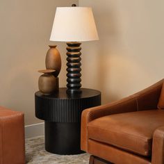 a lamp sitting on top of a table next to a brown chair and footstool