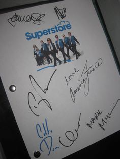 a bunch of autographed items are on a white sheet of paper with blue writing