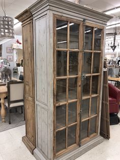 an old wooden cabinet with glass doors in a store display area at a furniture store