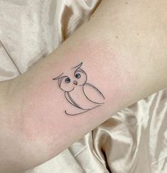 a small owl tattoo on the arm