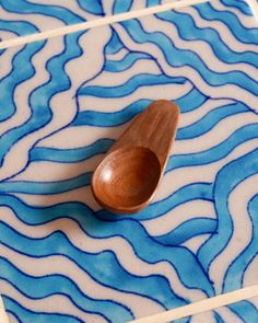 a wooden spoon sitting on top of a blue and white tile floor with wavy designs