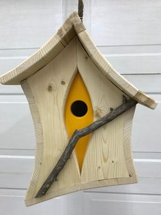 a yellow birdhouse hanging from a tree branch