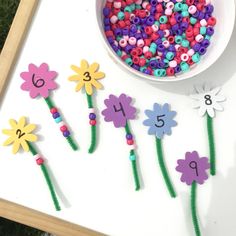 flowers and beads are arranged in the shape of numbers next to a bowl of beads