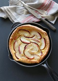 an apple pie in a cast iron skillet next to a fork and napkin on a table