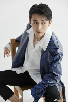 a young man sitting on top of a wooden chair