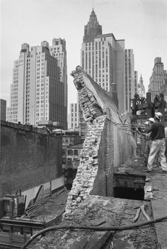 black and white photograph of men working on the roof of a building in new york city