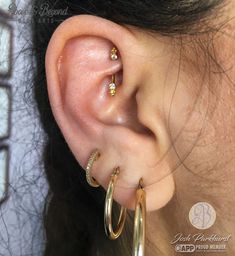 a close up of a person wearing gold hoop earrings with diamond accents on their ears