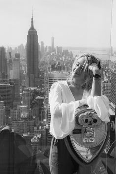 a woman standing on top of a tall building with a camera in front of her