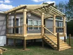 a wooden deck with stairs leading to the upper floor and second story on a mobile home