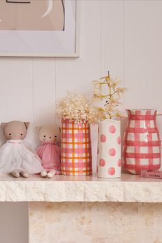 there are many vases on the mantle with flowers and stuffed animals next to them