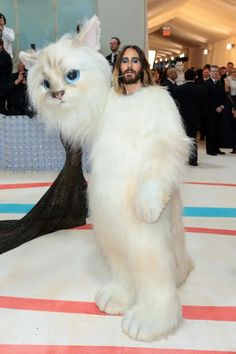 a man with long hair and blue eyes is dressed in an animal costume as he stands on