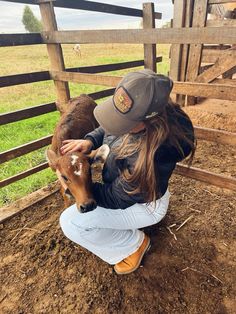 a woman kneeling down petting a baby goat