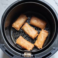 some food is being cooked in an air fryer on the counter top and it looks like they have wontons