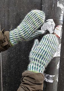 someone wearing mittens and gloves leaning against a pole