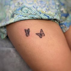 two small butterflies on the back of a woman's thigh, both with black ink